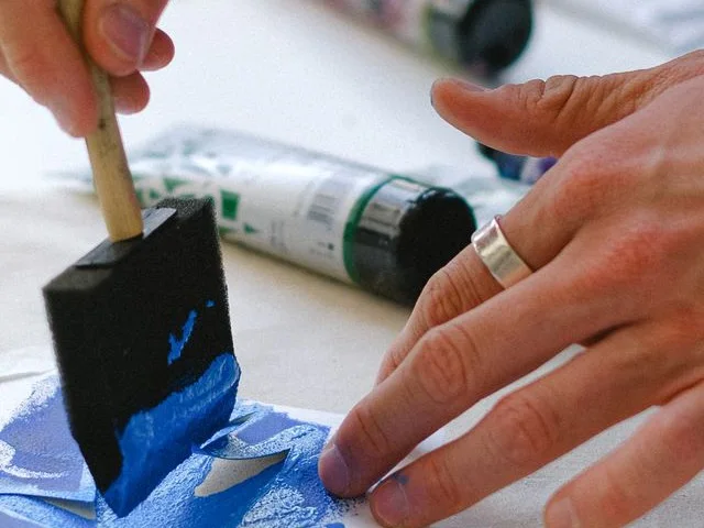 Díszítő festő sablonnal és ecsettel mintát fest, felirat- és reklámfestési gyakorlaton